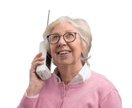 Téléchargez les photos : Heureuse femme âgée parlant avec un vieux téléphone sans fil, elle sourit et écoute - en image libre de droit