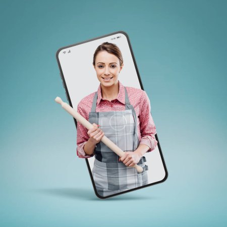 Photo for Young smiling housewife posing with rolling in a smartphone videocall and smiling, online  service concept - Royalty Free Image