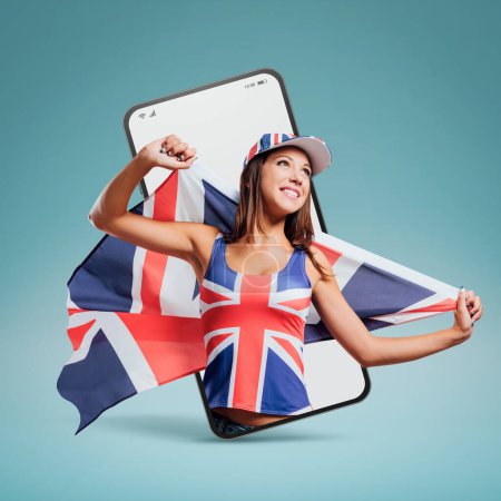 Foto de Alegre linda chica británica sosteniendo una bandera en un videocall smartphone y sonriendo - Imagen libre de derechos