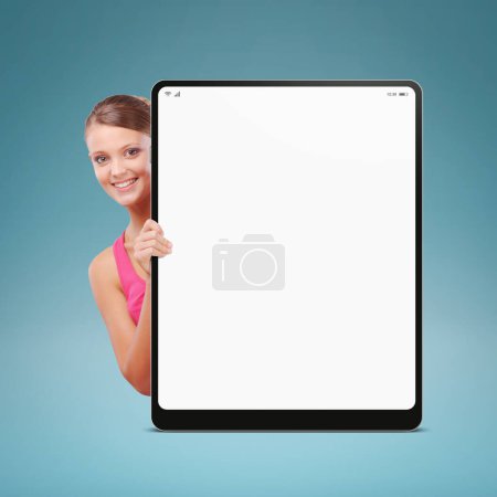 Foto de Mujer joven feliz mostrando una tableta digital en blanco y sonriendo - Imagen libre de derechos