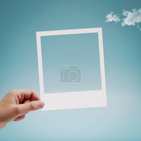Foto de Mano femenina sosteniendo una foto instantánea vintage, espacio para copiar, cielo azul en el fondo - Imagen libre de derechos