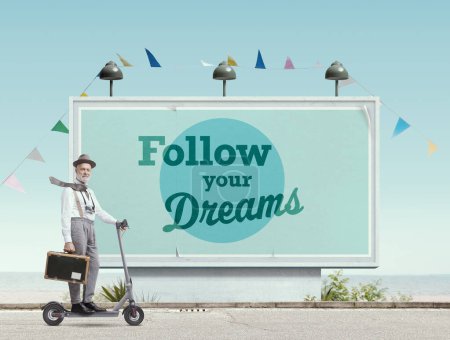 Téléchargez les photos : Heureux voyageur de style vintage chevauchant un e-scooter et un grand panneau d'affichage avec une citation motivante : suivez vos rêves - en image libre de droit
