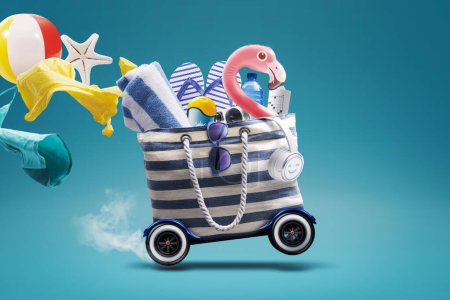 Photo for Inflatable flamingo and beach accessories in a fast bag with wheels, summer vacations at the beach concept, copy space - Royalty Free Image