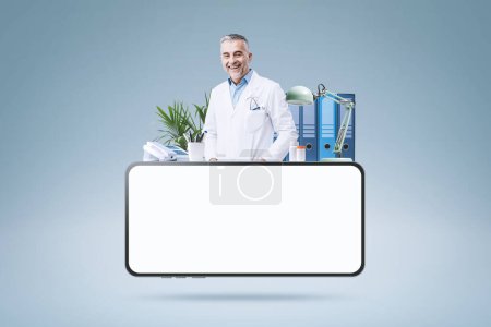 Photo for Professional doctor working in his office and smartphone with blank screen: telemedicine and online doctor concept - Royalty Free Image