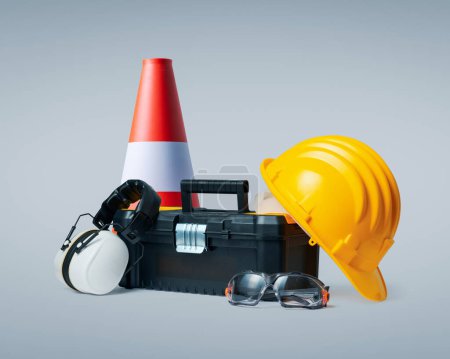 Construction worker tools and safety equipment: toolbox, hard hat, ear muffs, traffic cone and goggles