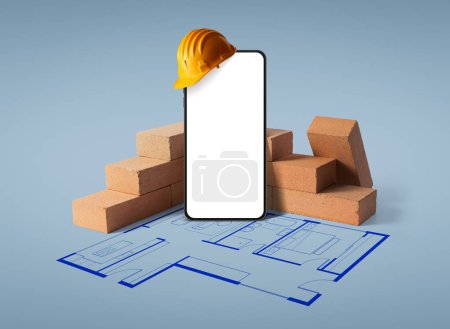 Téléchargez les photos : Smartphone avec écran vierge, briques et plan de maison : application de construction et de rénovation domiciliaires - en image libre de droit