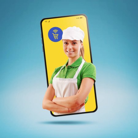Foto de Profesional sonriente empleado de supermercado posando en un teléfono inteligente, concepto de compras de comestibles en línea - Imagen libre de derechos