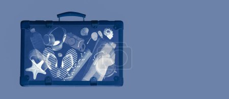Foto de X-ray scan of a suitcase with travel accessories inside, summer vacations concept, copy space - Imagen libre de derechos