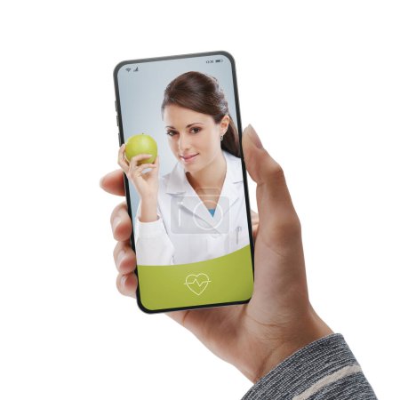 Photo for Patient video calling a nutritionist online on smartphone: online doctor video consultation on-demand - Royalty Free Image