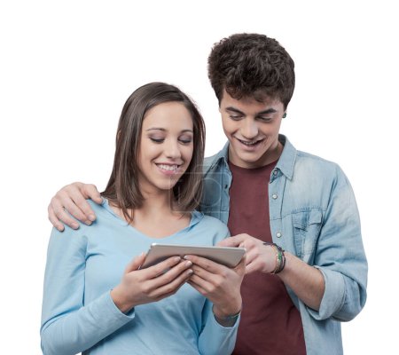 Téléchargez les photos : Adolescents joyeux utilisant une tablette à écran tactile et souriant - en image libre de droit