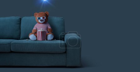 Foto de Osito de peluche sentado en el sofá y viendo películas en 3D en casa - Imagen libre de derechos