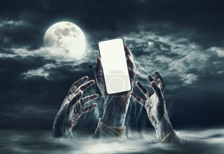 Foto de Zombie manos levantándose del suelo, uno está sosteniendo un teléfono inteligente con pantalla en blanco - Imagen libre de derechos
