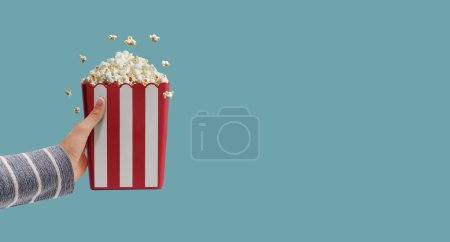Photo for Hand holding a box with popcorn, snacks and entertainment concept - Royalty Free Image