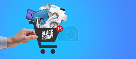Photo for Woman doing online shopping, she is holding a shopping cart icon full of goods, Black Friday sale concept - Royalty Free Image