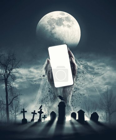 Foto de Espantosa mano zombi saliendo de una tumba y sosteniendo un teléfono inteligente con pantalla en blanco, espacio de copia - Imagen libre de derechos