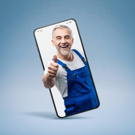 Photo for Cheerful repairman and plumber giving a thumbs up in a smartphone videocall and smiling, online  service concept - Royalty Free Image