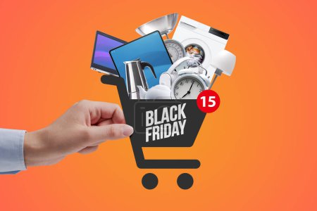 Photo for Woman doing online shopping, she is holding a shopping cart icon full of goods, Black Friday sale concept - Royalty Free Image