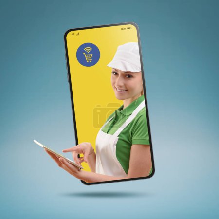Téléchargez les photos : Commis de supermarché souriant professionnel posant dans un smartphone, concept d'épicerie en ligne - en image libre de droit