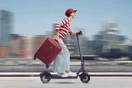 Téléchargez les photos : Femme touristique à la mode voyageant avec un scooter électrique, concept de mobilité durable - en image libre de droit