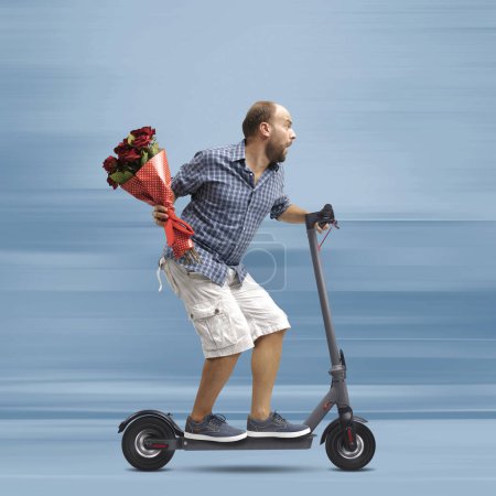 Photo for Man holding flowers and riding a fast electric scooter, he is late for his date - Royalty Free Image