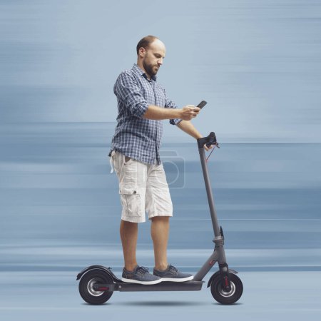 Téléchargez les photos : Homme négligent utilisant un smartphone tout en conduisant un scooter électrique - en image libre de droit