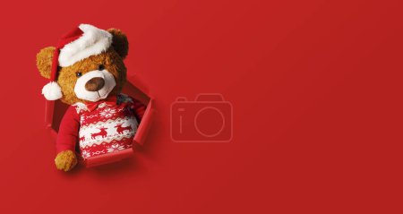 Photo for Cute Christmas teddy bear popping out of a hole in the paper, Christmas card with copy space - Royalty Free Image