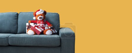 Téléchargez les photos : Ours en peluche mignon avec chapeau de Père Noël sur le canapé et de nombreux cadeaux, vacances et célébrations concept - en image libre de droit
