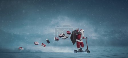 Téléchargez les photos : Père Noël contemporain chevauchant un scooter la nuit de la veille de Noël et portant des cadeaux, bannière avec espace de copie - en image libre de droit