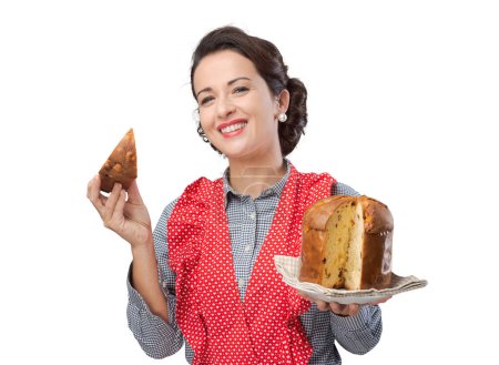 Foto de Mujer vintage en delantal comiendo una rebanada de panettone, pastelería casera tradicional italiana - Imagen libre de derechos