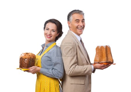 Téléchargez les photos : Couple vintage souriant à la maison tenant fait maison panettone et pandoro - en image libre de droit