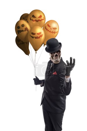 Foto de Espeluznante personaje de terror sosteniendo globos de Halloween y mirando a la cámara - Imagen libre de derechos