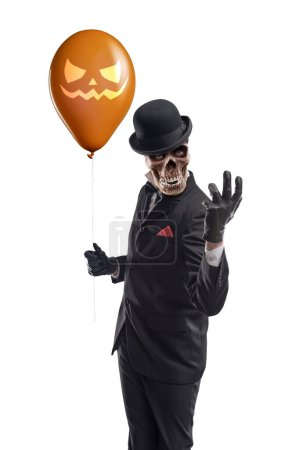 Foto de Espeluznante personaje de terror sosteniendo globos de Halloween y mirando a la cámara - Imagen libre de derechos