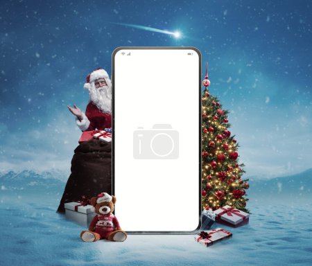Téléchargez les photos : Grand smartphone avec écran vierge, Père Noël, cadeaux et décorations : Achats de Noël en ligne - en image libre de droit