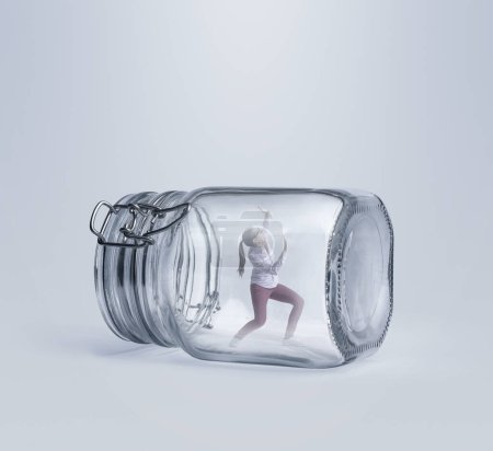Foto de Mujer joven asustada atrapada en un enorme frasco de vidrio, está desesperada e incapaz de escapar - Imagen libre de derechos