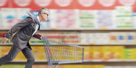 Foto de Rápido hombre de negocios corriendo y empujando un carrito de compras de supermercado - Imagen libre de derechos