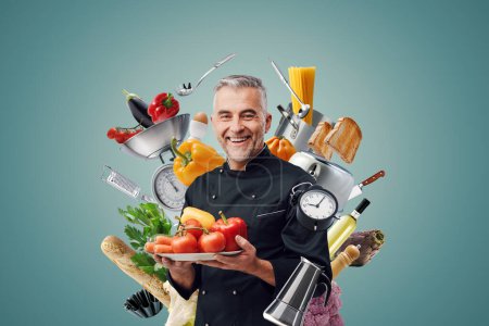 Foto de Chef sonriente rodeado de ingredientes alimentarios y utensilios de cocina profesionales: restaurantes y concepto de cocina creativa - Imagen libre de derechos