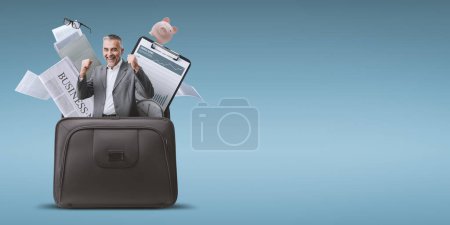 Foto de Alegre hombre de negocios celebrando con las armas levantadas y artículos de oficina en un maletín: exitoso concepto de negocios e inversiones - Imagen libre de derechos