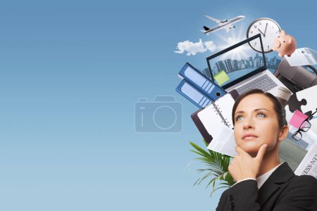 Photo for Confident pensive businesswoman with business items and office supplies around her head, she is making plans for her business and her career - Royalty Free Image