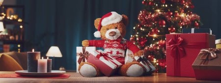 Téléchargez les photos : De nombreux cadeaux de Noël et mignon ours en peluche avec chapeau de Père Noël à la maison, Noël et vacances concept - en image libre de droit