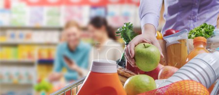 Téléchargez les photos : Femme mettant épicerie fraîche dans le panier à l'épicerie, épicerie et concept de vente au détail, espace de copie - en image libre de droit