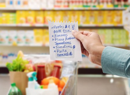 Téléchargez les photos : Femme au supermarché achetant des produits d'épicerie et tenant une liste d'achats, prise de vue - en image libre de droit