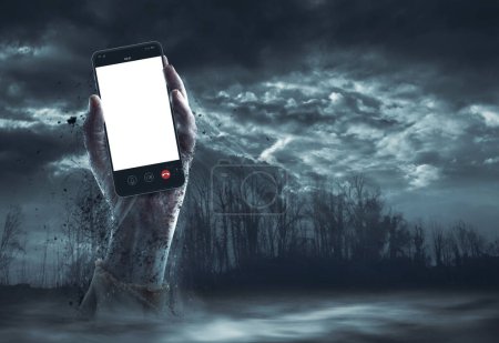 Foto de Espeluznante mano zombie sosteniendo un teléfono inteligente con pantalla en blanco, horror y concepto de Halloween - Imagen libre de derechos