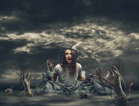 Téléchargez les photos : Terrifiée jeune femme dans son lit entouré de zombies, d'horreur et de cauchemars concept - en image libre de droit