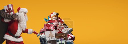 Téléchargez les photos : Père Noël rapide poussant un panier plein de cadeaux de Noël, concept d'achat de Noël - en image libre de droit