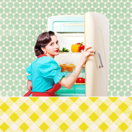 Téléchargez les photos : Femme au foyer de style vintage dans la cuisine préparant le déjeuner, elle ouvre le réfrigérateur et regarde la caméra - en image libre de droit