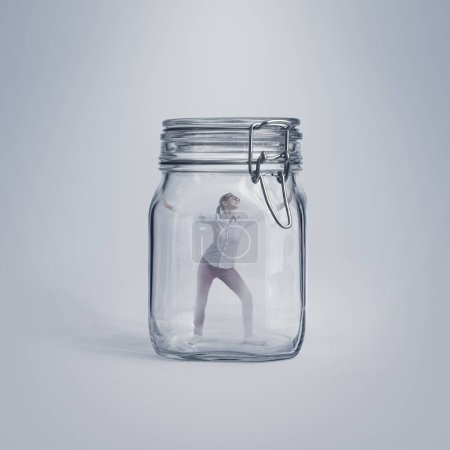 Foto de Mujer joven asustada atrapada en un enorme frasco de vidrio, está desesperada e incapaz de escapar - Imagen libre de derechos