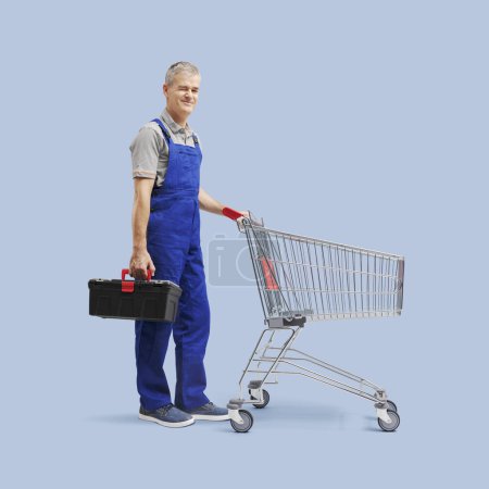 Photo for Professional repairman pushing an empty shopping cart and smiling at camera - Royalty Free Image