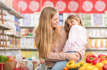 Téléchargez les photos : Portrait d'une mère heureuse tenant sa fille à l'épicerie, ils se sourient, épicerie et concept de style de vie - en image libre de droit