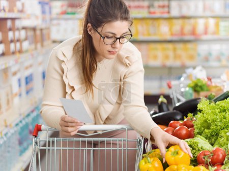 Téléchargez les photos : Femme faisant des courses au supermarché, elle achète des légumes frais biologiques dans la section des produits - en image libre de droit