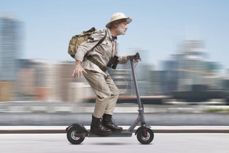 Téléchargez les photos : Amusant explorateur urbain senior chevauchant un scooter électrique rapide dans la rue de la ville - en image libre de droit